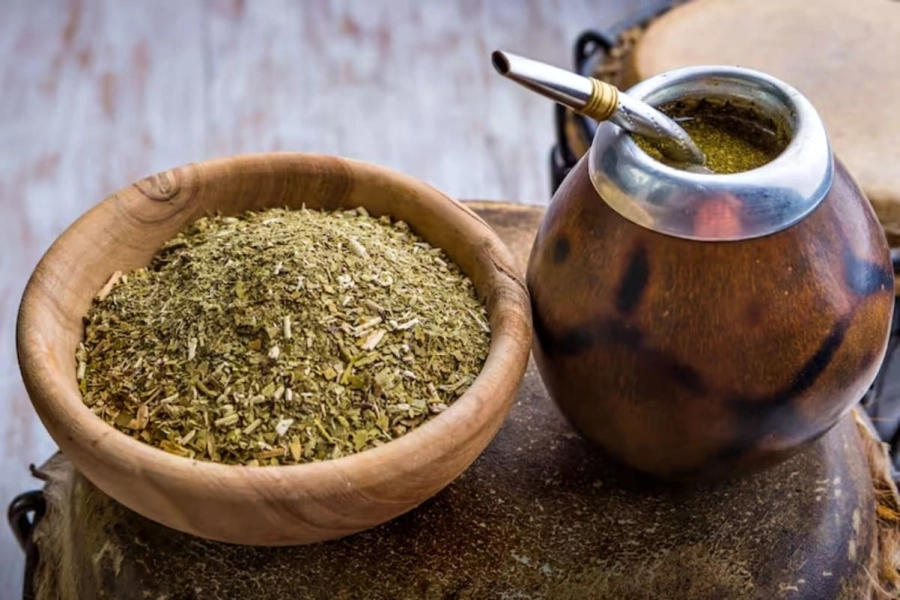 Hojas secas de yerba mate y mate tradicional, representando el uso tradicional del mate para la energía diaria.