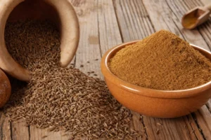 Semillas y polvo de comino secas, representando el uso tradicional del comino para la digestión y el bienestar cotidiano.