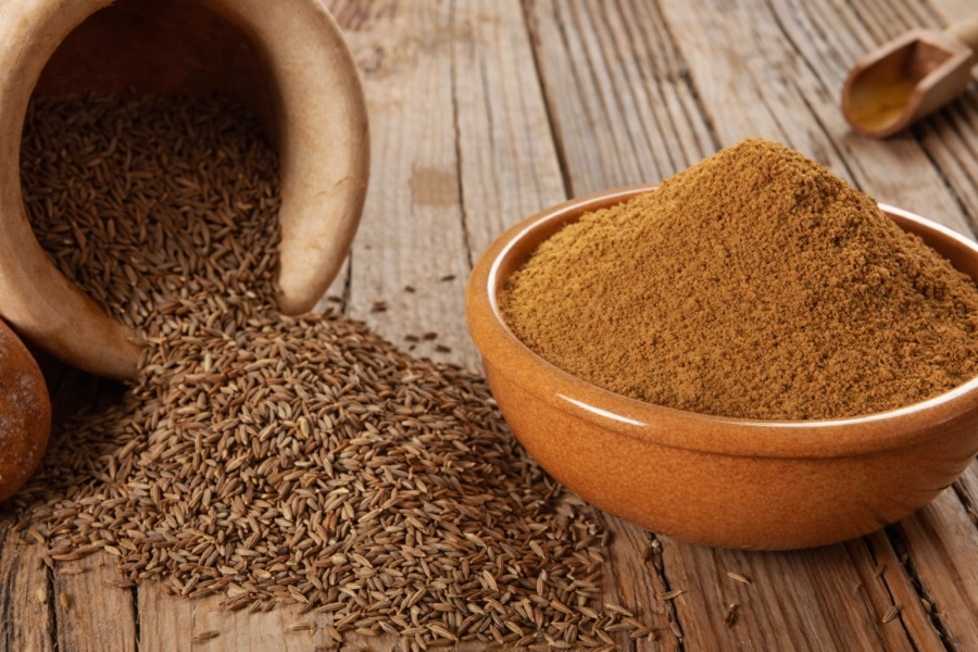 Semillas y polvo de comino secas, representando el uso tradicional del comino para la digestión y el bienestar cotidiano.